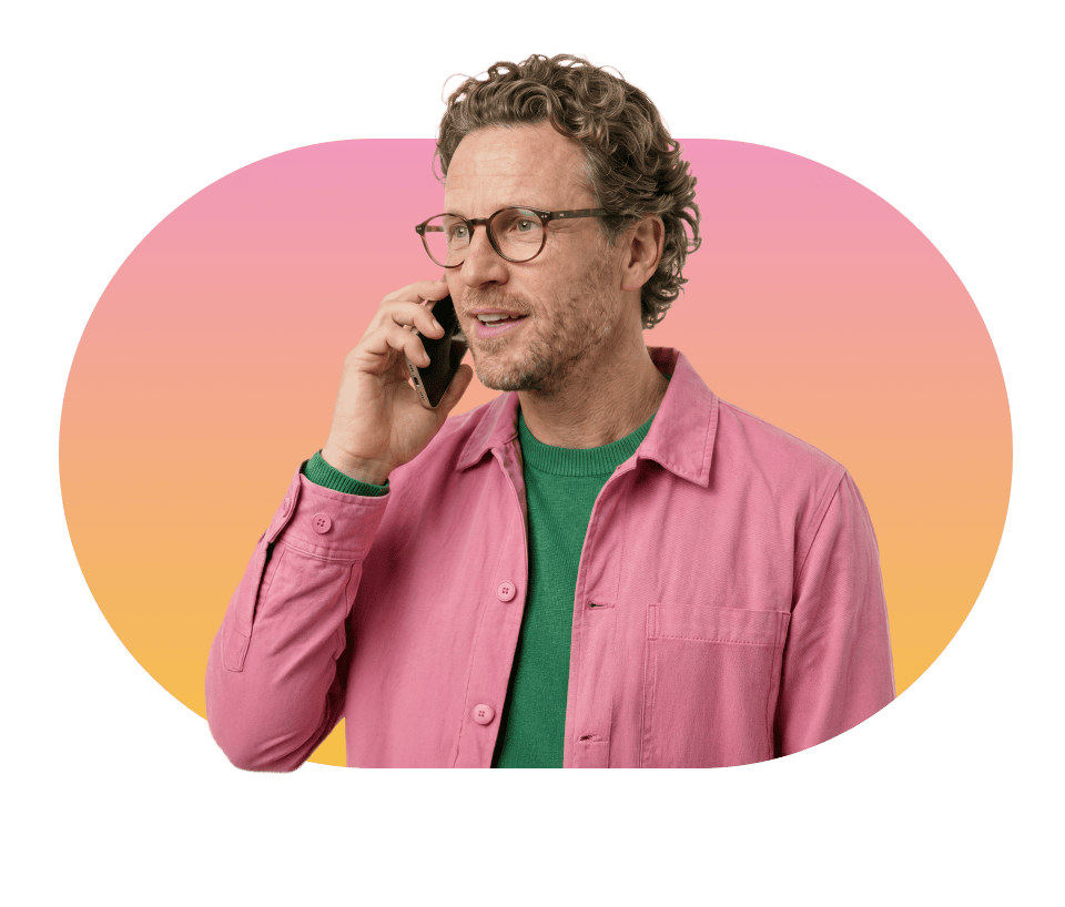 Robert van Rinkel in casual kleding aan de telefoon lachend kijkend in de camera