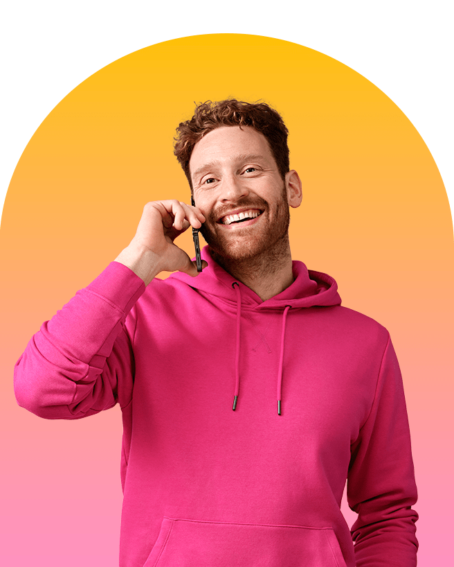 Robert van Rinkel is glimlachend aan het telefoneren in casual kleding met gele-roze gradient op de achtergrond