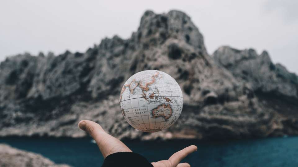 A globe hovering above a hand in relation to an international business phone number