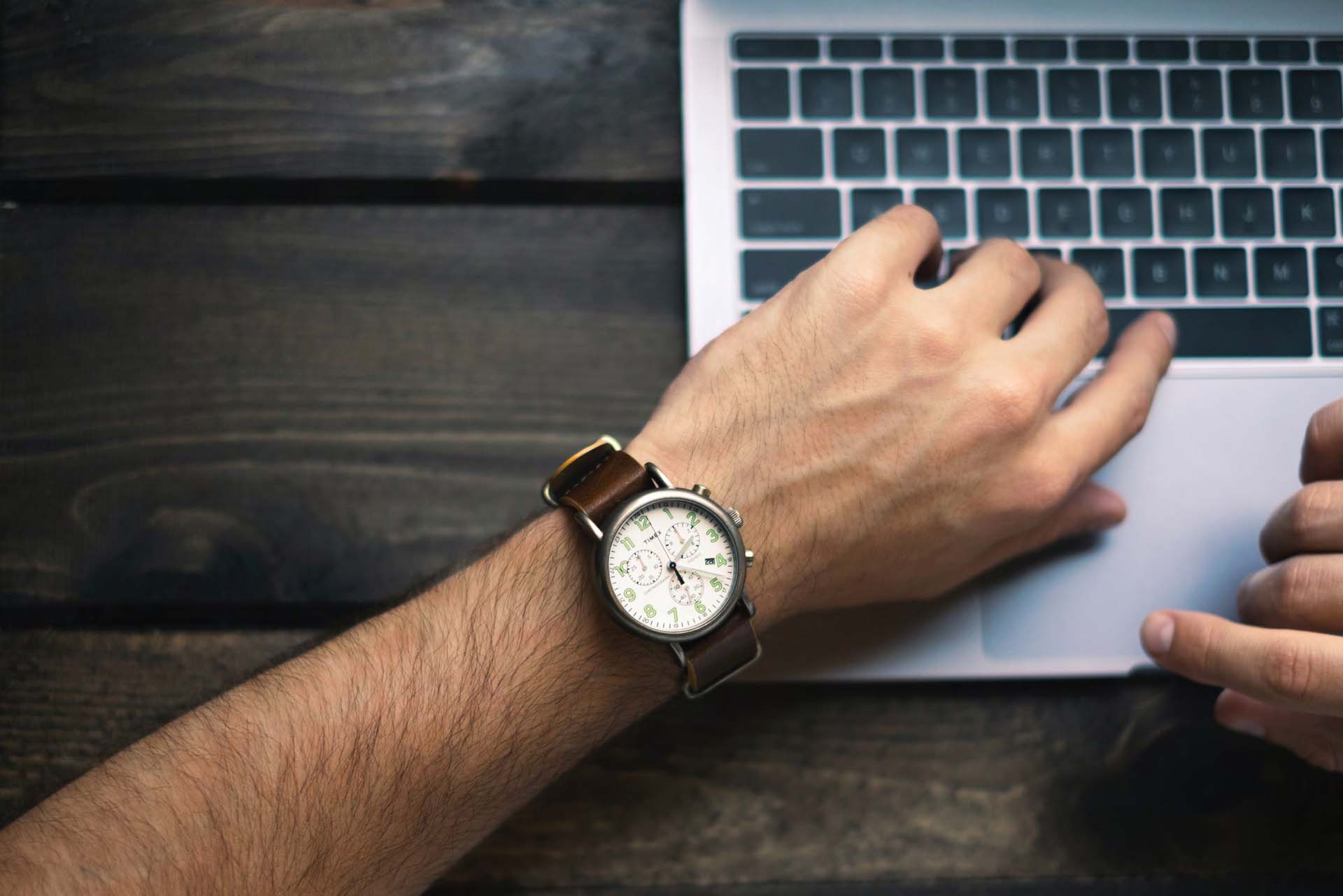 Een persoon op zijn of haar laptop met horloge om