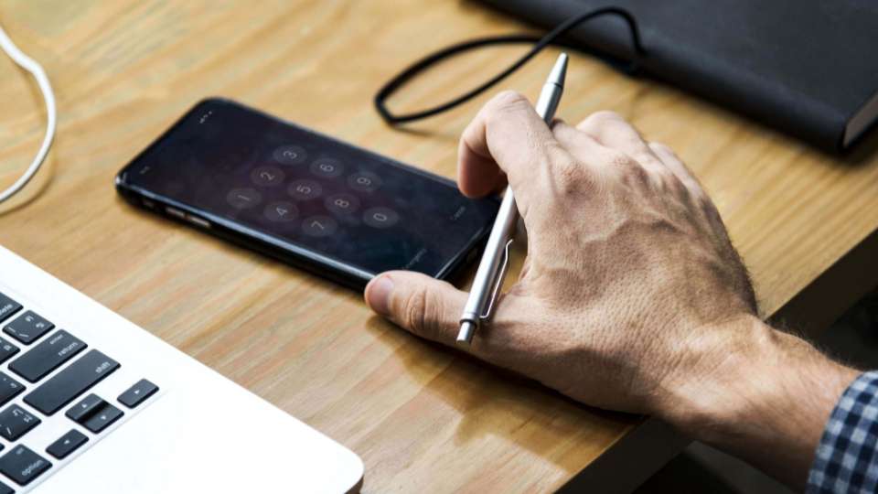 Telefoon met belscherm op bureau naast laptop