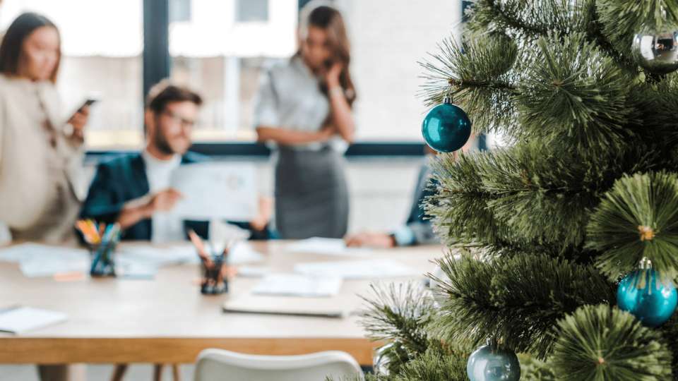 Mensen aan het werk in kantoor met kerstboom op de voorgrond