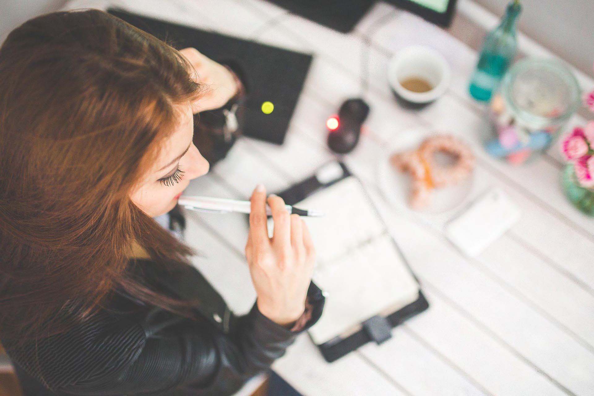 Vrouw is aan het nadenken over wat of hoe ze iets moet opschrijven