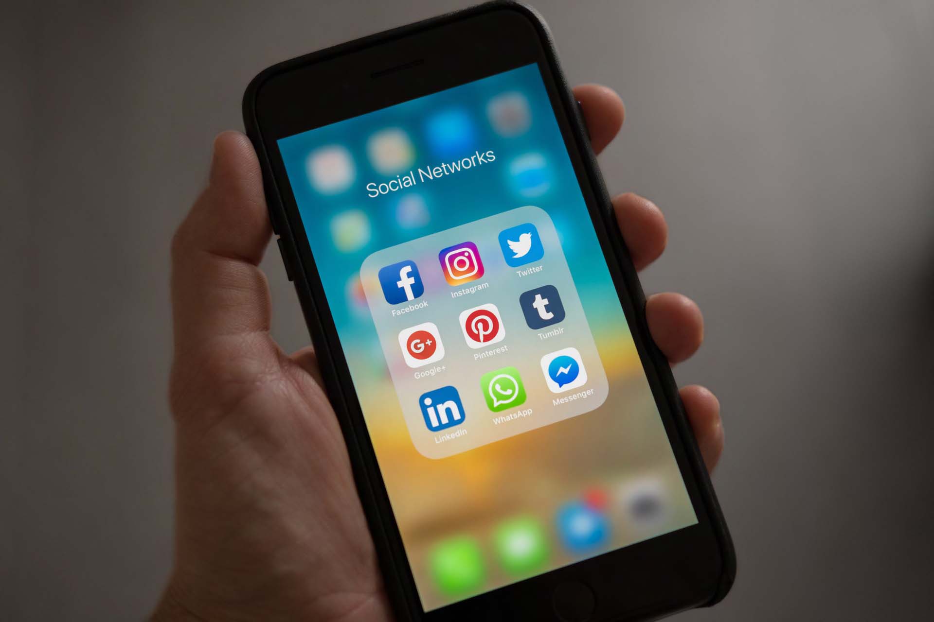 Persoon houdt iPhone vast waarop logo's van sociale media staan